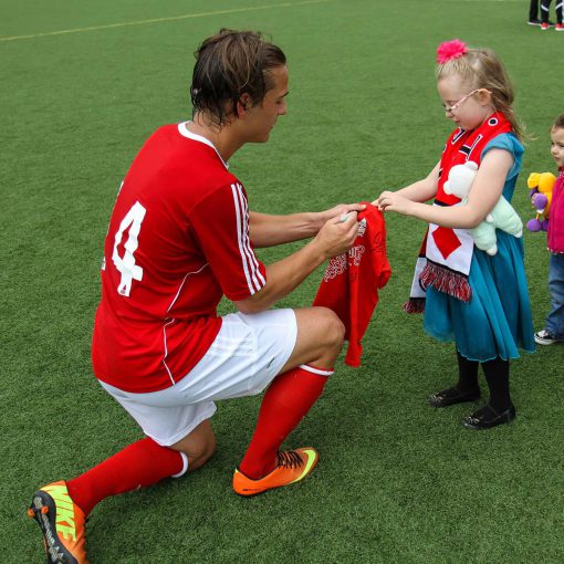 Lane United FC soccer player signs autograph for a little girl.